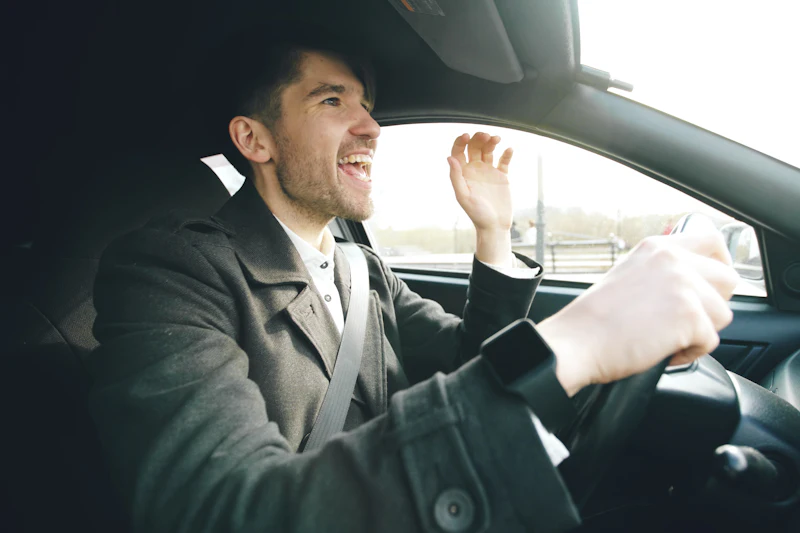 Homem sorrindo e cantando ao volante do carro